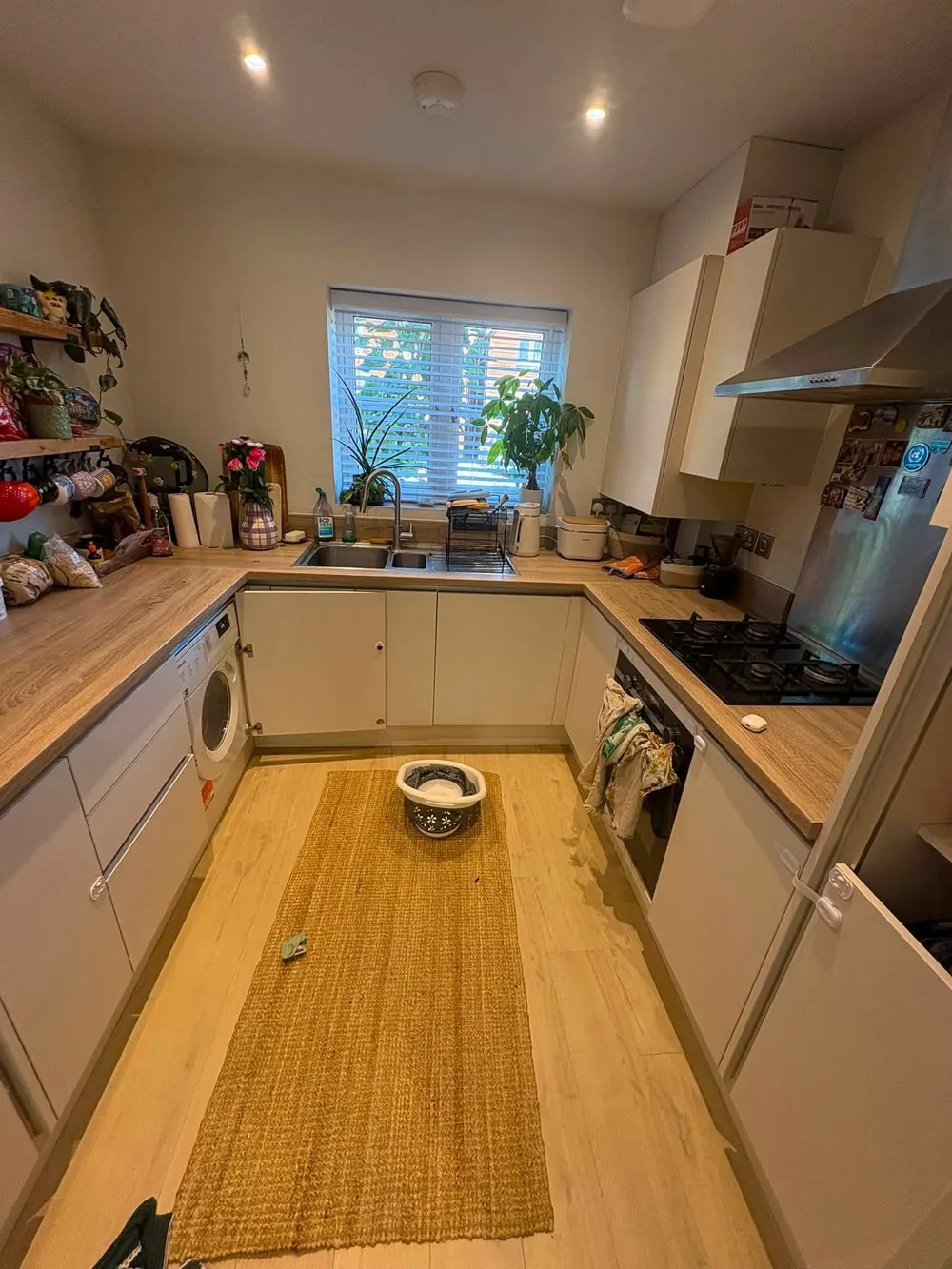 Kitchen before cleaning, with cluttered worktops and marked floor