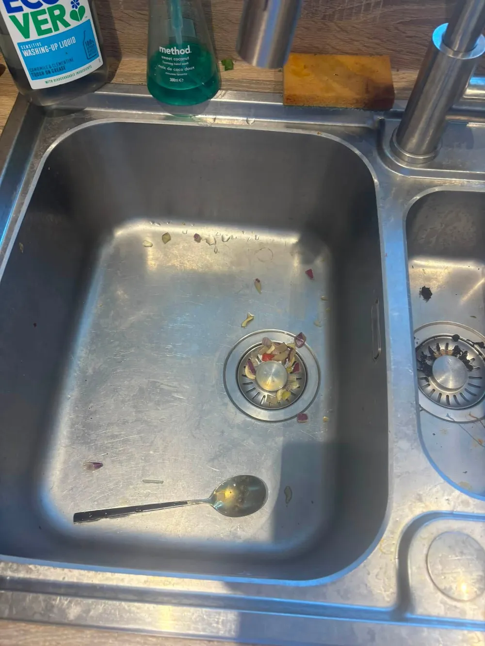 Kitchen sink before cleaning, with food debris around the drain
